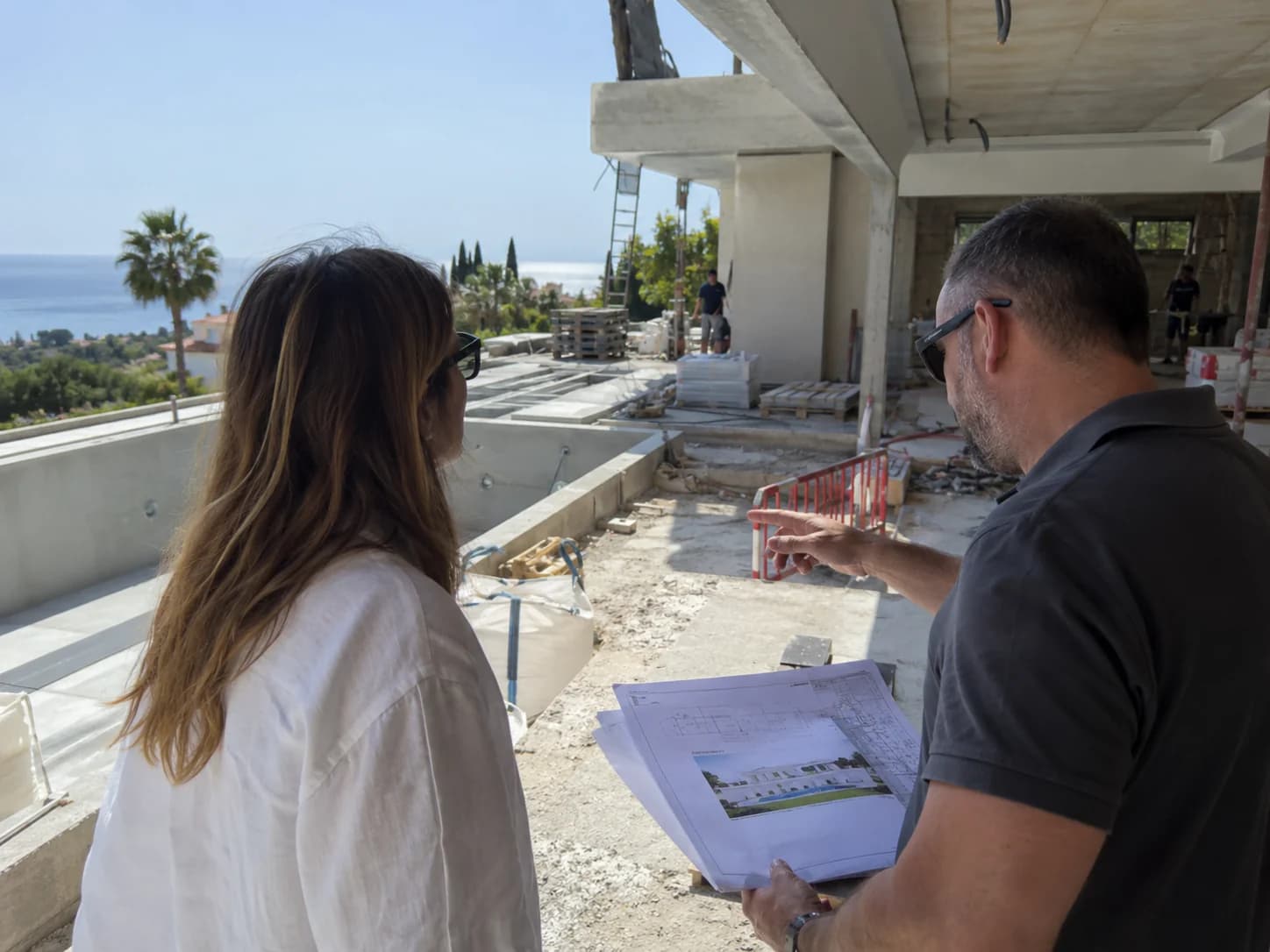 Client and site manager reviewing plans on a terrace under construction